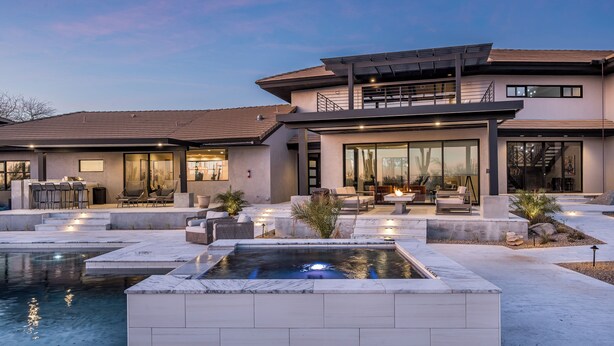 Una casa moderna con piscina, mobiliario exterior y un amplio patio.