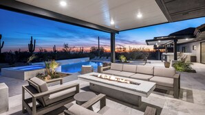 Un área exterior moderna con piscina, fogata y asientos cómodos.