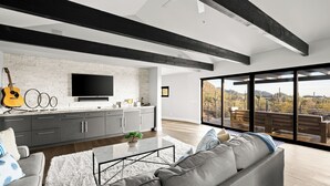 Una sala de estar moderna con un sofá gris, una mesa de centro y una guitarra en la pared.