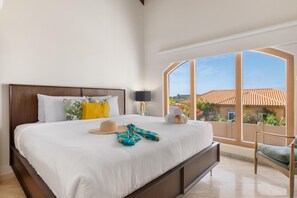 Ein Hotelzimmer mit einem großen Bett, Blick auf ein Gebäude mit roten Ziegeln und einem Balkon mit einem Stuhl.