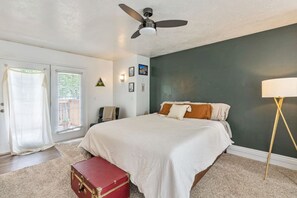 Une chambre à coucher avec un lit, un ventilateur de plafond, une valise et une lampe.