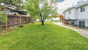 A backyard with a lawn, a wooden fence, and a house.