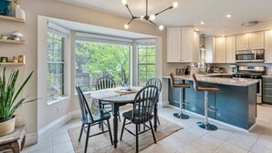 A modern kitchen with a central island, built-in appliances, and a dining area with a round table and chairs.