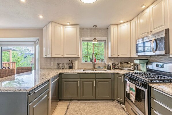 A kitchen with a granite countertop, stainless steel appliances, and a view of the outdoors.