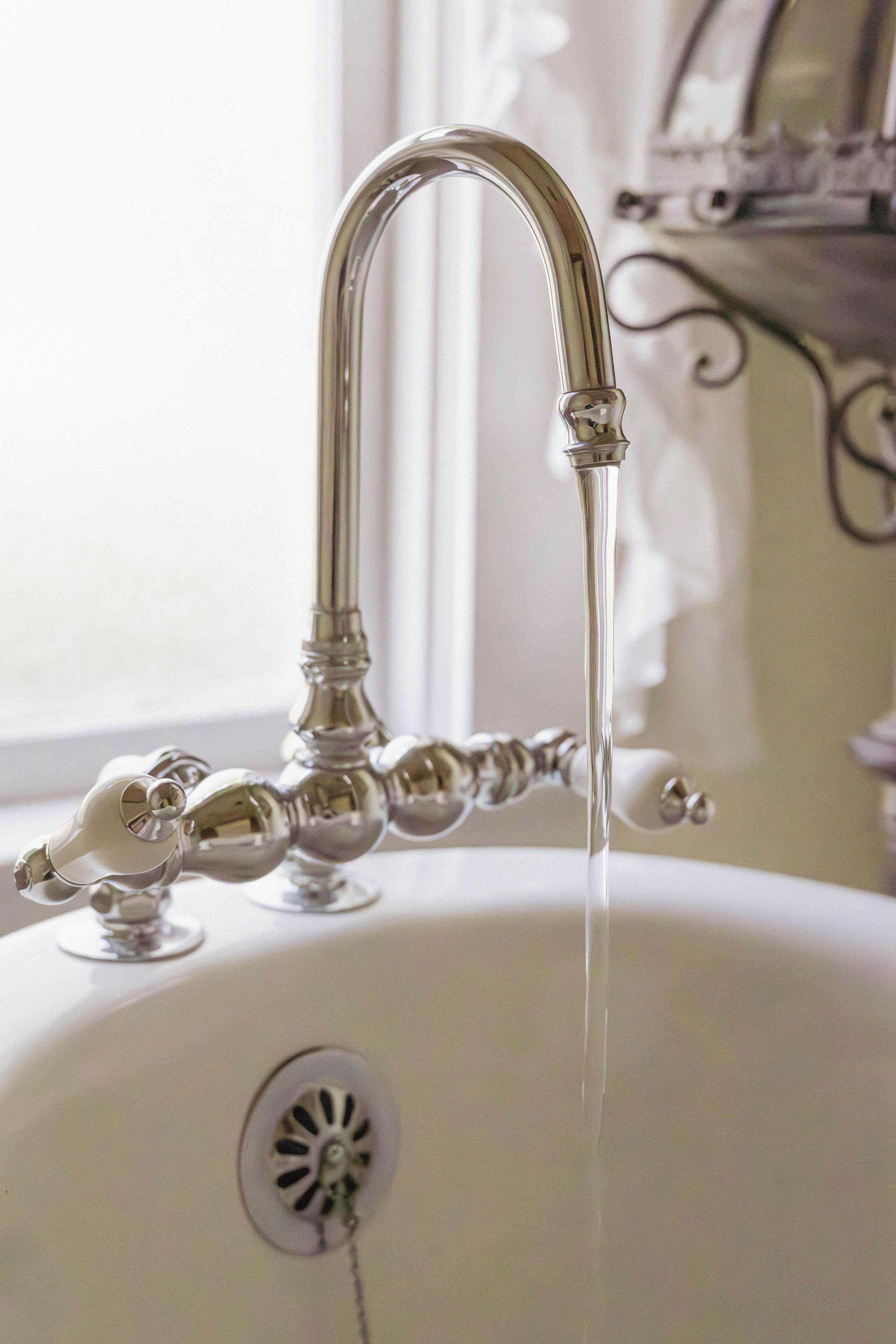 Un grifo de estilo antiguo con agua fluyendo en un lavabo blanco.
