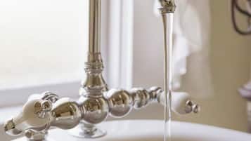 Un grifo de estilo antiguo con agua fluyendo en un lavabo blanco.