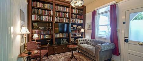 A cozy living room with a large bookshelf, a plush sofa, a small table, and a patterned rug.