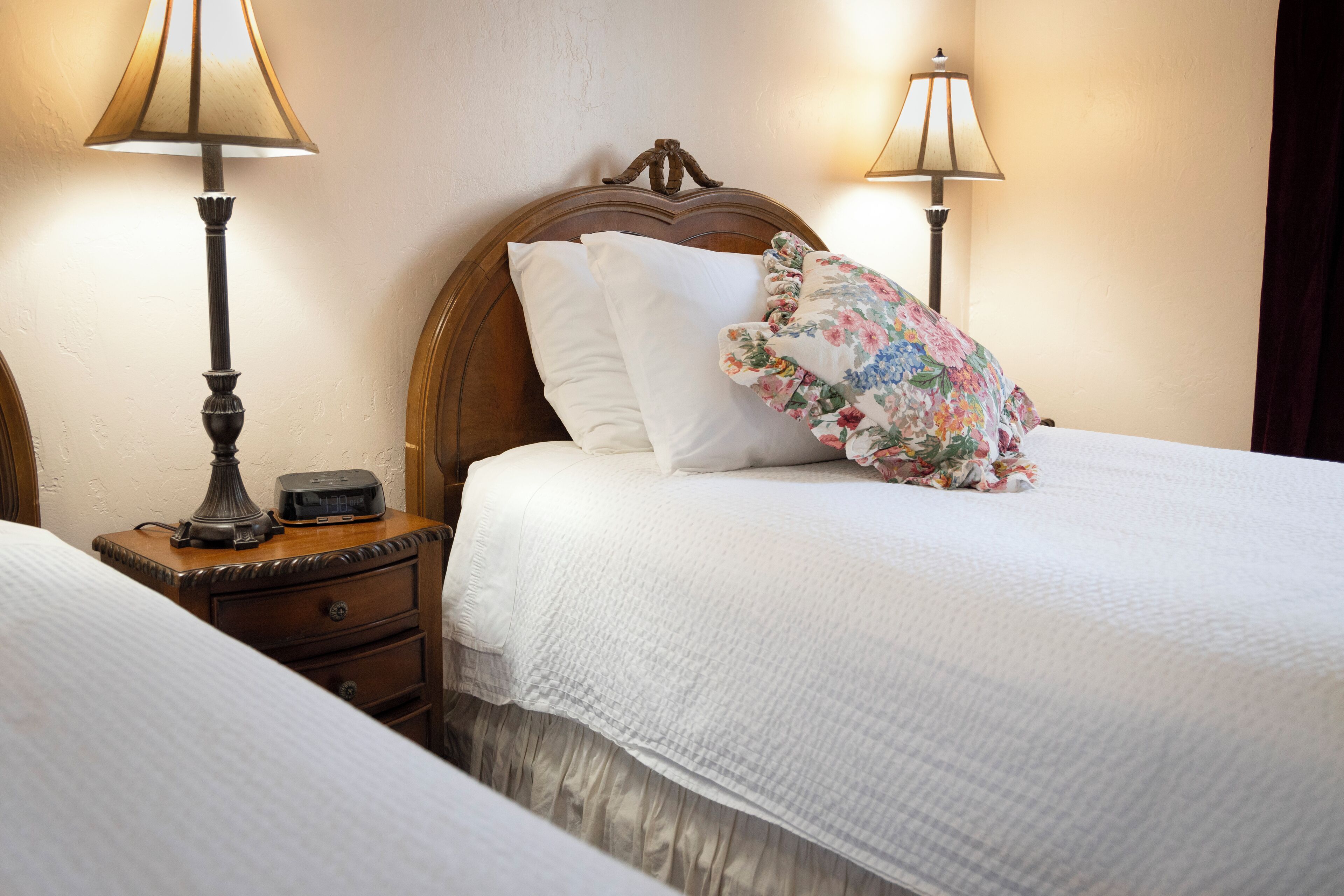 A neatly made double bed with white bedding, a wooden headboard, and two bedside lamps.