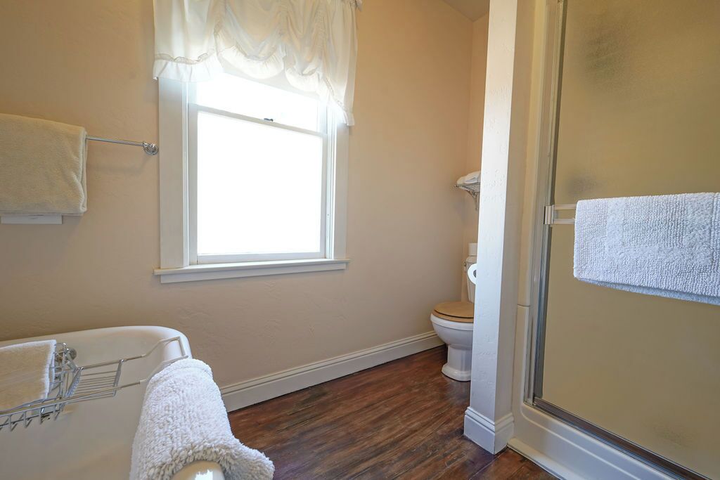 A bathroom with a bathtub, toilet, and a glass shower enclosure.