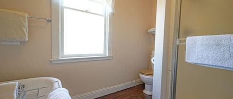 A bathroom with a bathtub, toilet, and a glass shower enclosure.
