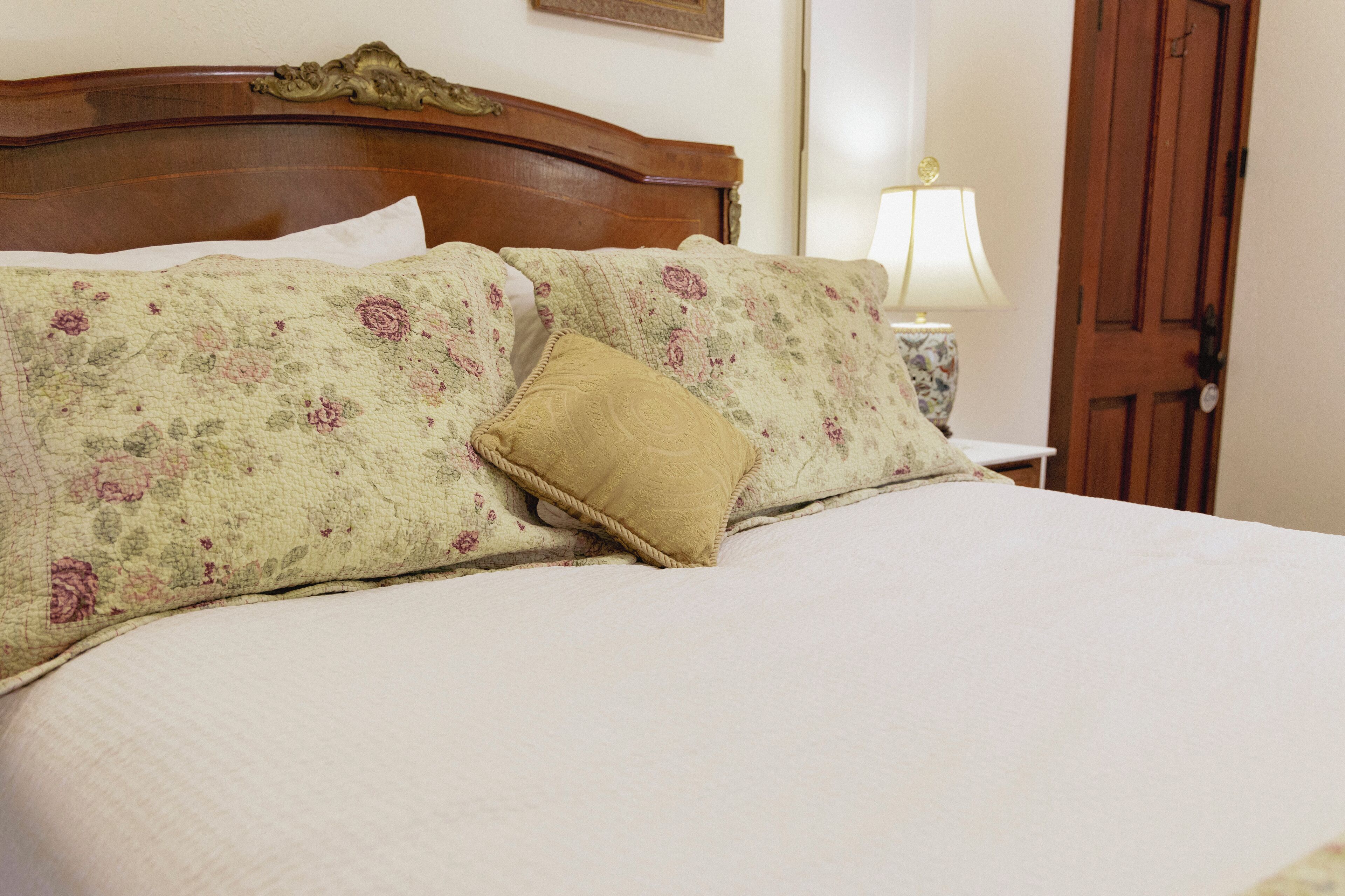 Una cama con ropa de cama floral, un cabecero de madera y una lámpara de noche.