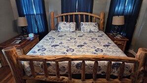 A wooden-framed bed with a patterned bedspread, two bedside tables with lamps, and a chandelier. - Charming 3-bedroom house in tranquil Oraville minutes from  Kinkaid Lake.   (Oraville)