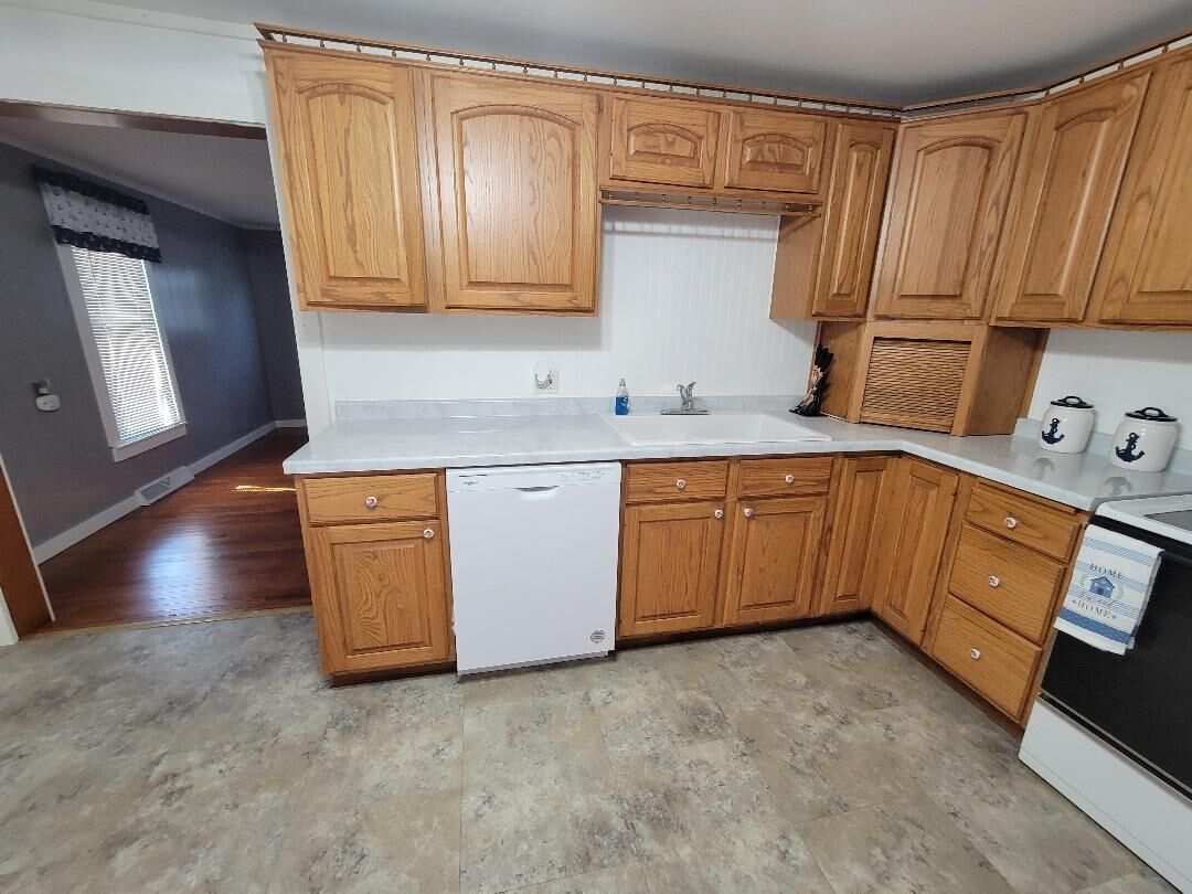 Une cuisine avec des meubles de rangement en bois, un lave-vaisselle et une cuisinière.