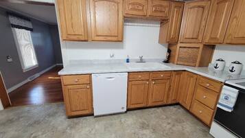 Une cuisine avec des meubles de rangement en bois, un lave-vaisselle et une cuisinière.