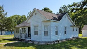 A single-story house with a front porch, a small front yard, and a blue fence in the background. - Charming 3-bedroom house in tranquil Oraville minutes from  Kinkaid Lake.   (Oraville)