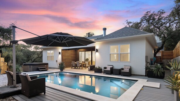 Una casa moderna con piscina, arredi da esterno e un patio.