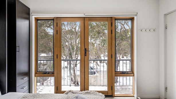 A bedroom with a large sliding glass door leading to a balcony. - Hangar - Dinner plain (Dinner Plain)