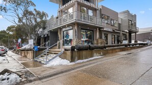 A corner building with a ski and board rental sign, a staircase leading to the entrance, and a stone wall in front. - Hangar - Dinner plain (Dinner Plain)