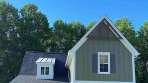A two-story house with a front porch, a red door, and a flag. - Rooted Lake Cottage w/ Golf Cart - NEW to VRBO! (Tullahoma)