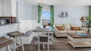Un salon moderne avec un coin repas, offrant une vue sur la plage par la fenêtre.