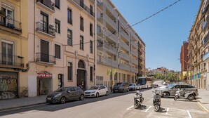 A street with multi-story buildings, parked cars, and scooters. - GuestReady - Lovely home in the heart of Barcelona (Barcelona)