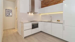 A modern kitchen with white cabinetry, a stainless steel range hood, a built-in oven, and a sink. - GuestReady - Lovely home in the heart of Barcelona (Barcelona)