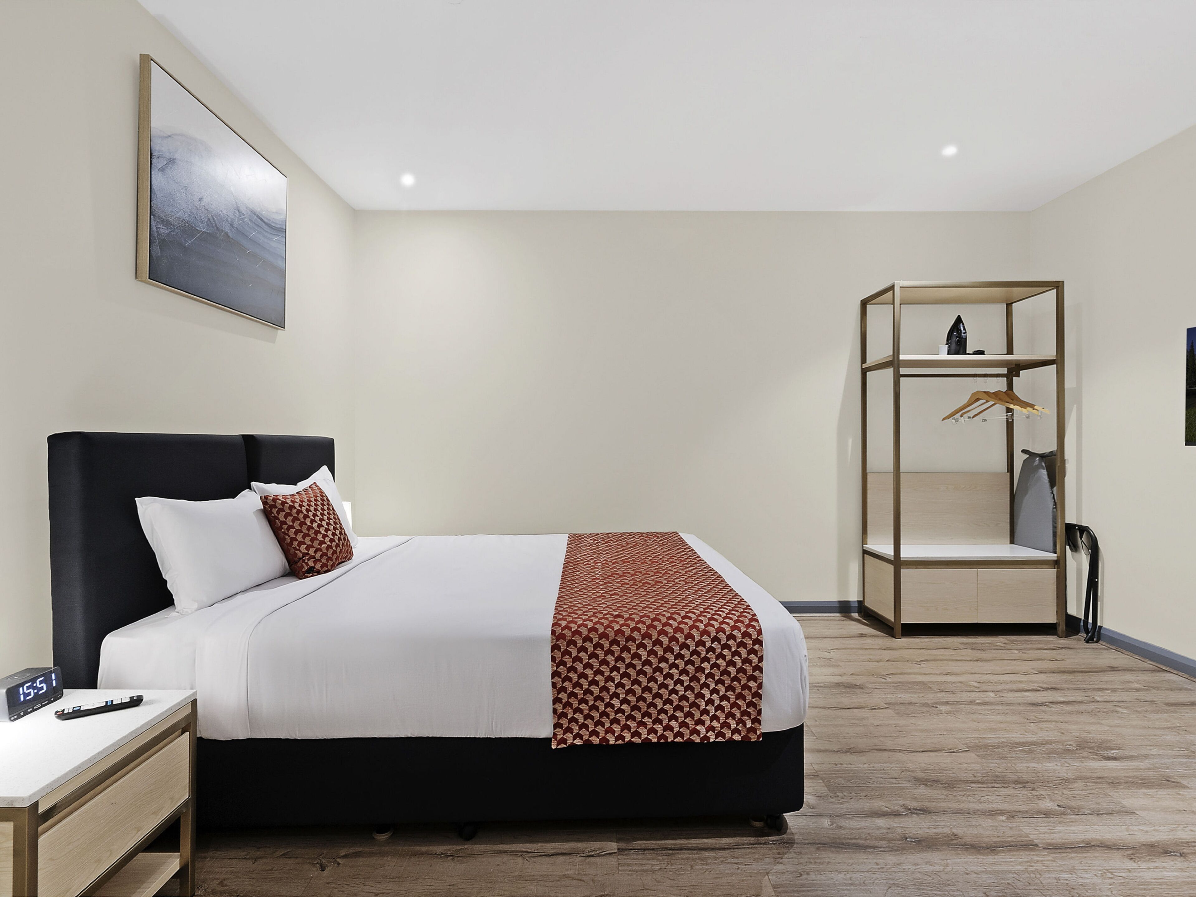 Et moderne hotelværelse med seng, sengebord og indbygget skab.