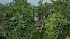 Una casa rodeada de un bosque frondoso con vista a un lago extenso.