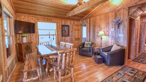 Un interior de madera con una mesa de comedor, sillas, un sofá y un televisor.