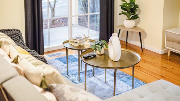 A cozy living room with a sofa, a coffee table, and a small side table with a plant and books. - StayAU Cozy Family Comfort 5BRM Glen (Glen Waverley)