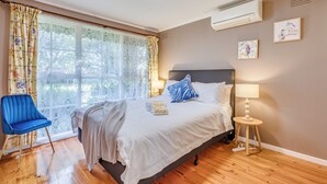 A bedroom with a bed, a blue chair, a bedside table with a lamp, and a window with curtains. - StayAU Cozy Family Comfort 5BRM Glen (Glen Waverley)