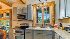 A kitchen with granite countertops, stainless steel appliances, and wooden cabinetry. - 3 bedroom cottage, peaceful and private, with pool, fitness, flowers and nature (Buda)