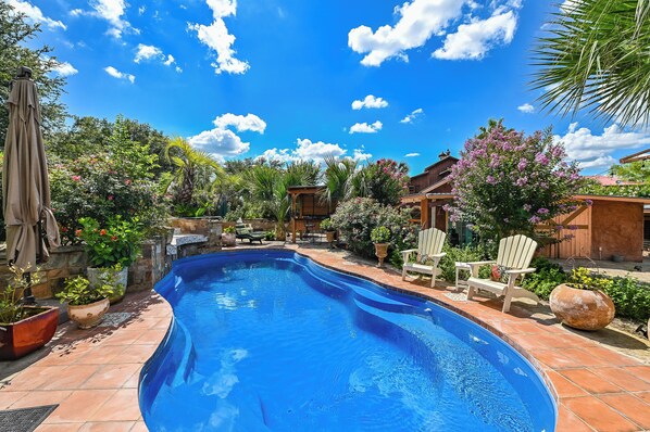 Una piscina rodeada de exuberante vegetación y mobiliario de patio.