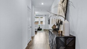 A hallway with a dark console table, white walls, and a wooden floor.