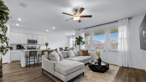 A modern living room with a sofa, coffee table, and a dining area with bar stools.