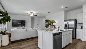 A modern kitchen with white cabinetry, a built-in dishwasher, and a stainless steel refrigerator.