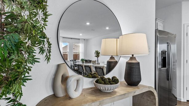 A modern kitchen with a large mirror, a wooden countertop, a bowl of decorative balls, a lamp, and a stainless steel refrigerator.