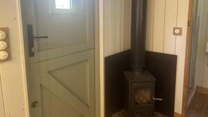 Ein Zimmer mit Holztür, einem schwarzen Herd und einem kleinen Fenster.