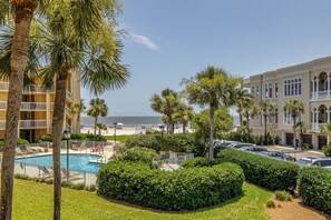 Et hotel med pool, palmer og udsigt til stranden.