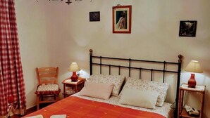 A bedroom with a bed, two bedside tables, a chair, and a red plaid curtain. - At the Oven Door (Roccascalegna)