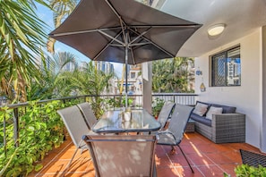An outdoor patio with a glass table, chairs, and a sofa.