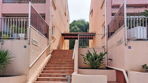 Un conjunto de escalones exteriores que conducen a la entrada de un edificio, con barandilla de metal y plantas en macetas.