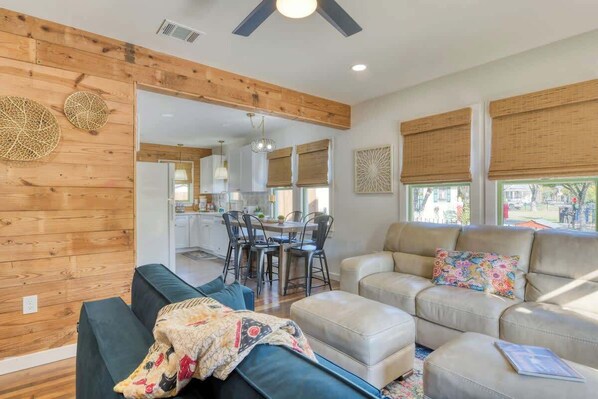 A spacious living area with a sofa, ottoman, and a dining table with chairs.