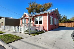 A single-story house with a red exterior and white trim, a front porch, and a white picket fence.