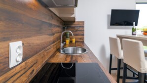 Une cuisine moderne avec des meubles en bois, un évier en acier inoxydable et une plaque de cuisson à induction noire.