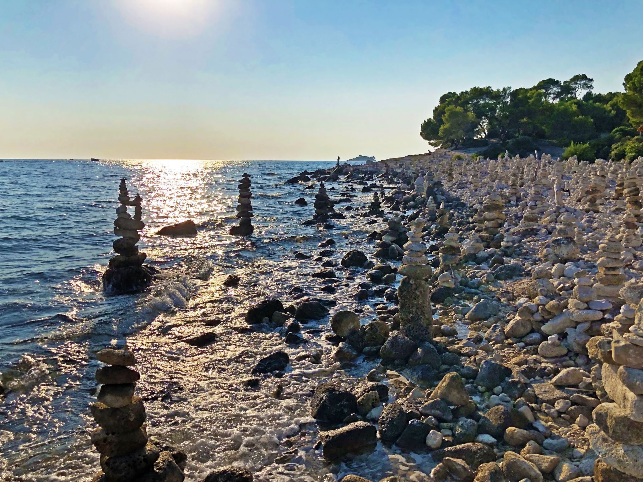 A rocky shoreline with stacks of stones and a clear view of the sea.