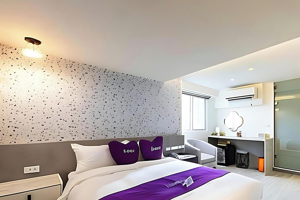 Quarto de hotel moderno com cama, escrivaninha, cadeira e closet espaçoso.