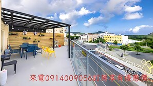 Un balcon aménagé avec du mobilier d’extérieur, une pergola et une vue sur un paysage urbain avec des bâtiments et une route.