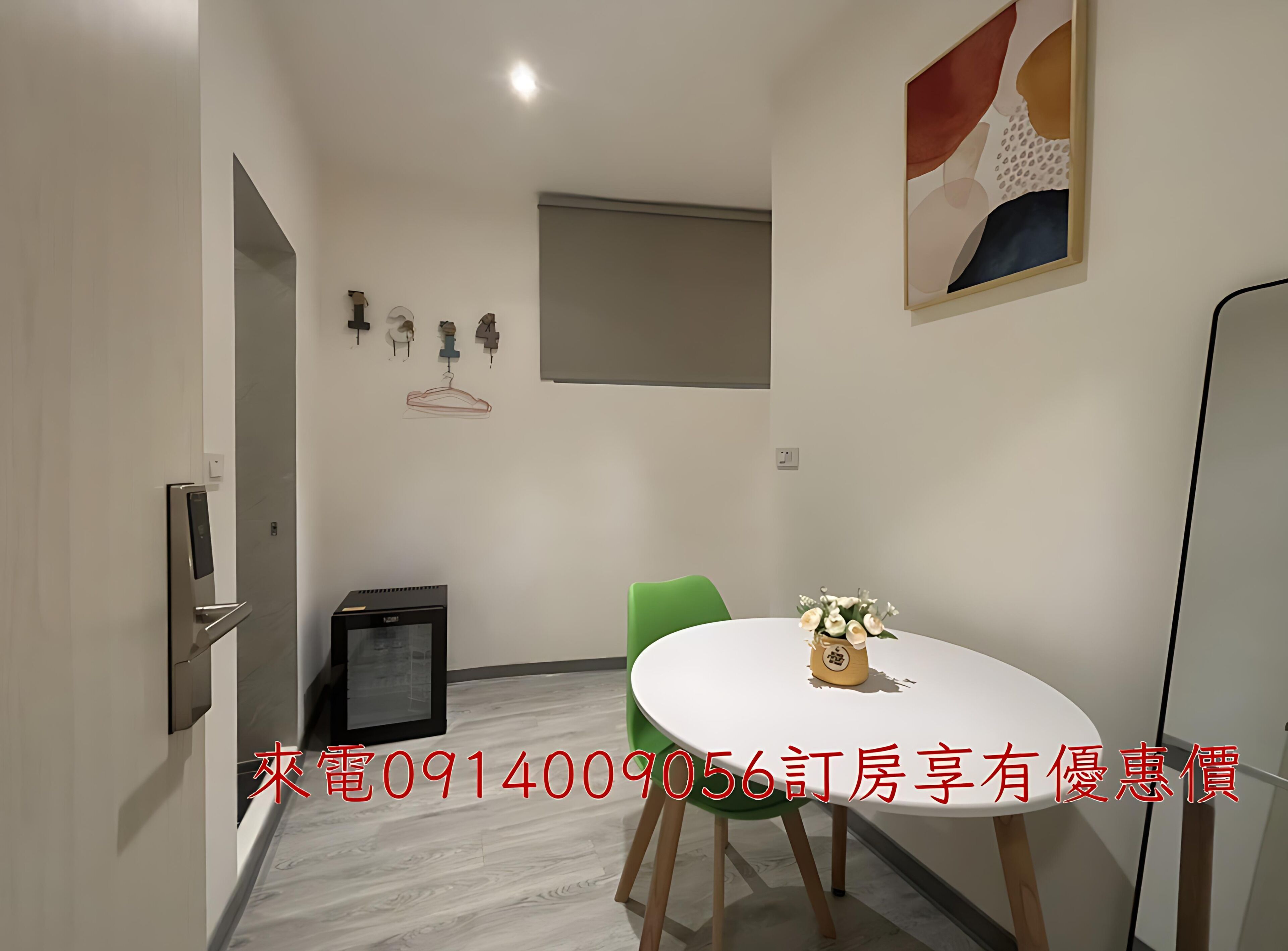 A modern room with a dining table, chairs, a small refrigerator, and a wall-mounted art piece.