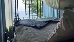 Une chambre avec un lit, une vue sur la mer et un luminaire suspendu.